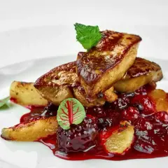 Tranches de foie gras poêlé, nappées d'une sauce aux fruits rouges, garnies d'une feuille de menthe et d'une petite feuille rouge. L'épice foie gras est sublimée par cette présentation.