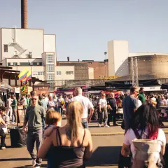 Menschen genießen das Street Food Festival Bergisch Gladbach mit vielen Essensständen und bunter Atmosphäre vor Industriebauten.