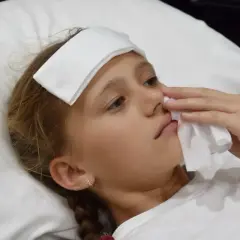 Bambina con impacco sulla fronte e fazzoletto per fermare il sangue dal naso.