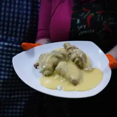 Porcja ryżu z kurczakiem w kremowym sosie potrawkowym, podana na białym talerzu.