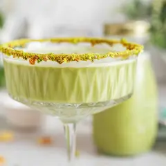 Zielony likier pistacjowy w kieliszku z posypką z pistacji. Idealny na specjalne okazje, oto prosty likier pistacjowy przepis.