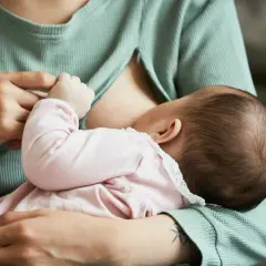 Mama karmi dziecko. Piersi są pełne mleka, co może powodować uczucie twardości przy karmieniu.