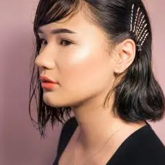 Ein Mädchen mit dunklen, nassen Haaren, die mit Glitzer-Haarnadeln geschmückt sind. So kann man seine **Haare richtig stylen** für einen besonderen Look.