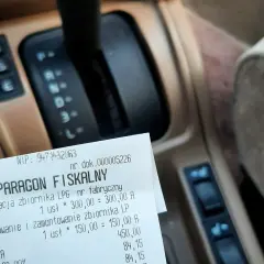Paragon fiskalny za legalizację i montaż zbiornika LPG na tle deski rozdzielczej samochodu.
