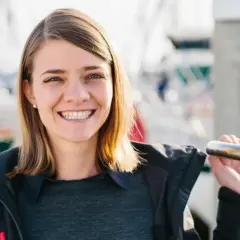 Uśmiechnięta Jessica Watson, która przetrwała sztorm, na tle łodzi.