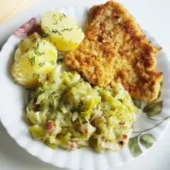 Młoda kapusta zasmażana z boczkiem, podana z ziemniakami i kotletem. Pyszny, domowy obiad.