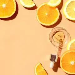 Krople serum z witaminą C w pipetce, otoczone plasterkami pomarańczy i cytryny. Pamiętaj, z czym nie łączyć witaminy C.