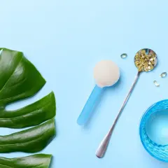 Grünes Monstera-Blatt, Löffel mit Kapseln, Pulver und Glas Wasser. Alles für die gleiche Wirkung.