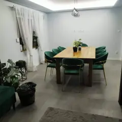 Elegancki salon w stylu glamour z zielonymi aksamitnymi krzesłami i drewnianym stołem.