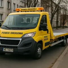 Żółty pojazd z napisem "POMOC DROGOWA" na masce i dachu, gotowy do akcji. Posiada licencję na pomoc drogową.