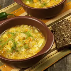 Kapuśniak jak u babci, pachnący koperkiem, podany z ciemnym chlebem. Obok papryczki i żółta papryka.