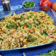 Zapiekanka z frytkami, kurczakiem, warzywami i serem, posypana natką pietruszki.