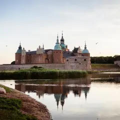 Ett ståtligt slott i Småland speglar sig i vattnet.