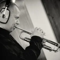 Piotr Wojtasik w słuchawkach gra na trąbce w studiu nagraniowym.