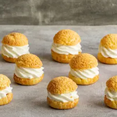 Douze petits choux pâtisseries garnis d'une crème onctueuse, prêts à être dégustés.