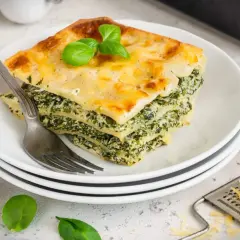 Ein Stück Spinatlasagne mit Käse überbacken, garniert mit Basilikum. Ein köstliches Rezept für jeden Tag.