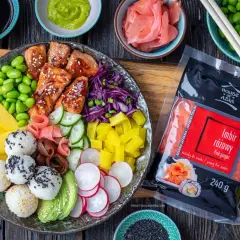 Kolorowy bowl z lososiem, ryżem, mango, awokado, edamame i marynowanym imbirem. Obok opakowanie imbiru różowego.