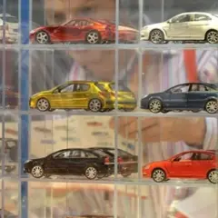 Modele samochodów w gablotach: białe kombi, czerwony sportowy, żółty hatchback, niebieski sedan, srebrny coupe.