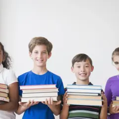 Vier lächelnde Kinder der 3. Klasse präsentieren stolz ihre Bücher für die buchvorstellung klasse 3.