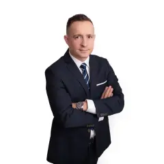 Mężczyzna w garniturze ze skrzyżowanymi rękami, na białym tle.