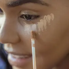Application d'anti-cerne sous l'œil, avant ou après fond de teint, pour un regard lumineux.