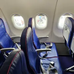 Puste siedzenia w samolocie Wizzair, przez okna widać ludzi na płycie lotniska. Automatyczna odprawa Wizzair przebiegła sprawnie.