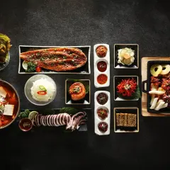 Zestaw koreańskich potraw: zupa, ryba, kalmar, kimchi, ryż i dodatki.