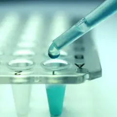 Kropla błękitnego płynu z pipety spada do probówki. To kluczowy etap w procesie leczenia biologicznego, gdzie precyzja jest najważniejsza.