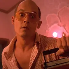 Raoul Duke z Las Vegas Parano, w okularach i wzorzystej koszuli, trzyma magnetofon.