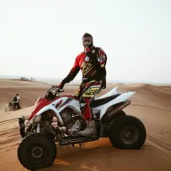 Mężczyzna w stroju motocyklowym siedzi na quadzie na pustyni.