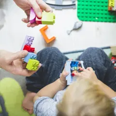 Dziecko i dorosły budują z kolorowych klocków. To wspaniałe, mądre zabawki, które rozwijają kreatywność i wyobraźnię.