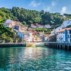 Un pueblo costero con casas coloridas se aferra a una colina verde. Un lugar perfecto para una escapada de pueblos con encanto.