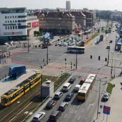 Żółty tramwaj na skrzyżowaniu z samochodami i autobusem.