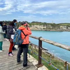 Disfrutando de las rutas por Santander, un grupo de amigos admira el faro y la costa desde un mirador de madera.