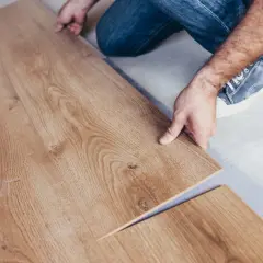 Installazione di un nuovo pavimento in laminare parquet. Le assi in legno chiaro vengono posate con cura.