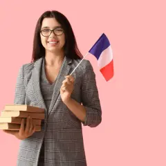 Uśmiechnięta kobieta w okularach trzyma stos książek i flagę Francji, gotowa by zostać francuskim pisarzem.