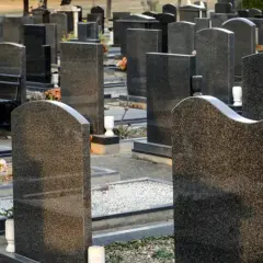 Nagrobki na cmentarzu, z kwiatami i ławką.