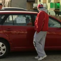 Czerwony samochód na sprzedaż z ogłoszeniem na szybie. Cena 26000. Zastanawiasz się, ile kosztuje wystawienie samochodu na OLX?