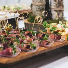 Eleganckie przekąski na desce, idealne na catering we Wrocławiu na imprezy. Roladki z szynki, rolmopsy z cukinii i inne smakołyki.