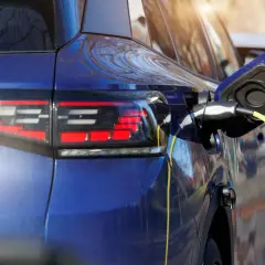 Niebieski samochód hybrydowy jest ładowany. To przyszłość motoryzacji, która łączy silnik spalinowy z elektrycznym.