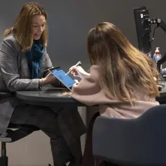 Dos mujeres revisan una tablet, discutiendo una posible hipoteca de 100.000 euros a 15 años.