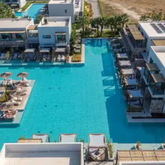 Luksusowy resort z basenami i leżakami przy plaży Caravia Beach Kos. Palmy i nowoczesna architektura tworzą idealne miejsce na relaks.