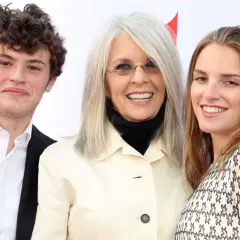 Diane Keaton z uśmiechem pozuje z dwójką swoich dzieci, synem i córką, na czerwonym dywanie.