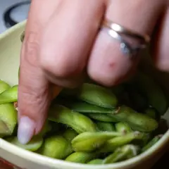 Ręka sięga po zielone strączki edamame w miseczce. Zdrowa przekąska, co zamiast Controloc?