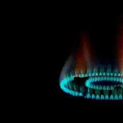 Fiamma gialla e blu di un bruciatore a gas, parte di una caldaia, che illumina il buio.