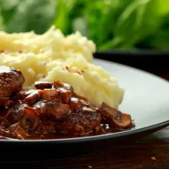 Délicieuses joues de bœuf mijotées dans une sauce aux champignons, servies avec une purée de pommes de terre onctueuse.
