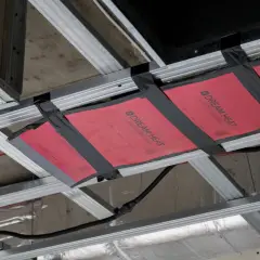 Instalacja grzejnika na podczerwień w suficie podwieszanym. Wady montażu widoczne na taśmie mocującej.