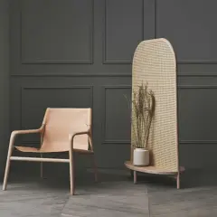 Stilvoller Raumteiler aus Rattan als alternative zu Tapete, neben einem Ledersessel.