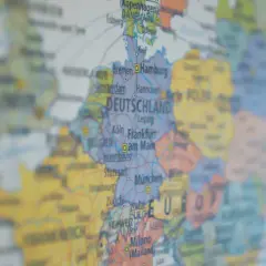 Mapa Europy z zaznaczoną DEUTSCHLAND. Widać miasta takie jak Hamburg, Frankfurt, Monachium. W tle widoczne są landy niemieckie, zakazy podróżowania w Europie.