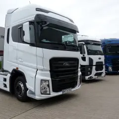 Trzy ciężarówki Ford F650 stoją obok siebie. Biała, biała i niebieska ciężarówka.